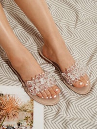 the feet of a woman wearing a pair of sandals with crystals